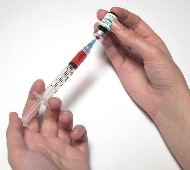syringe drawing from vaccine bottle