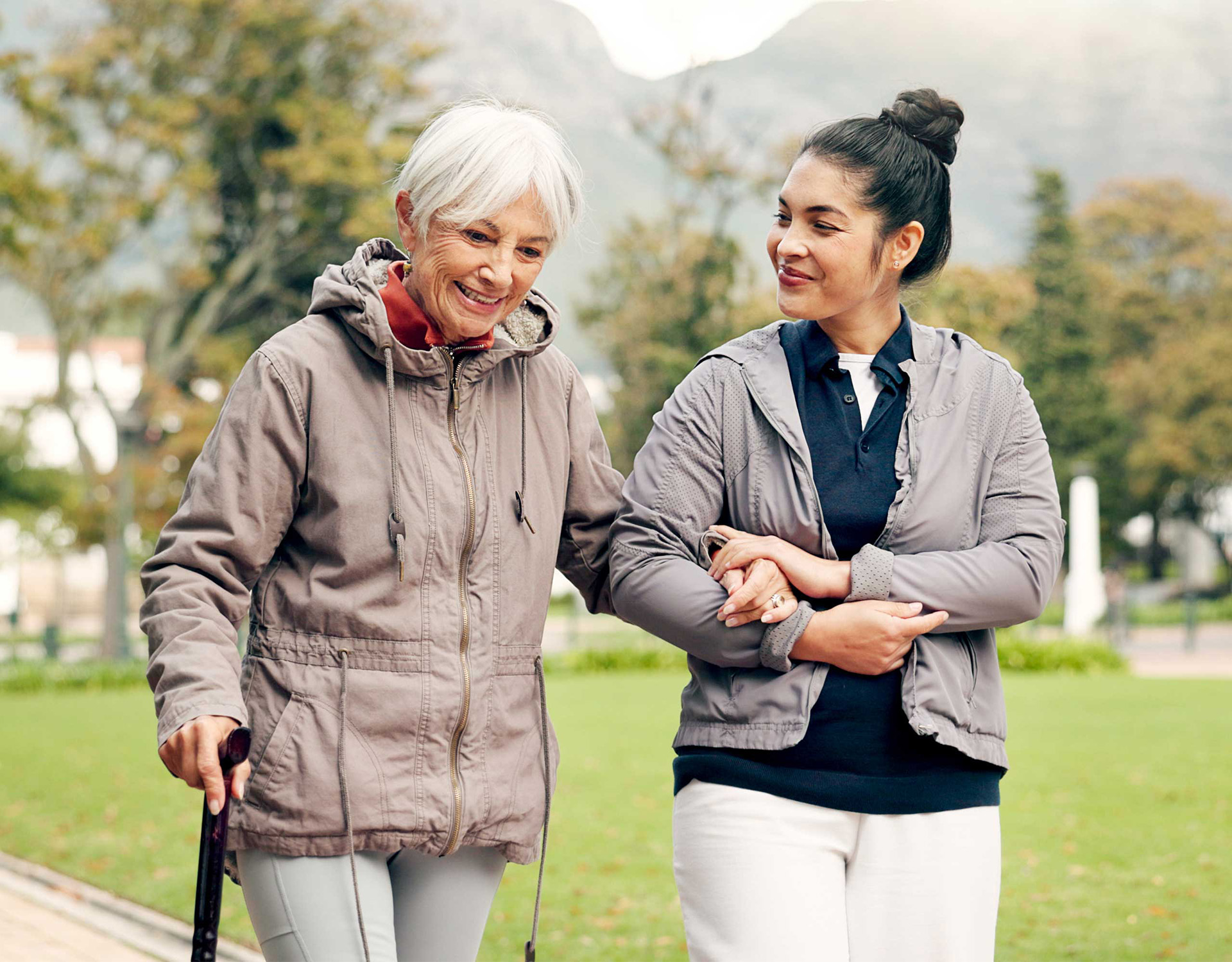 Woman assisting a woman using a cane.